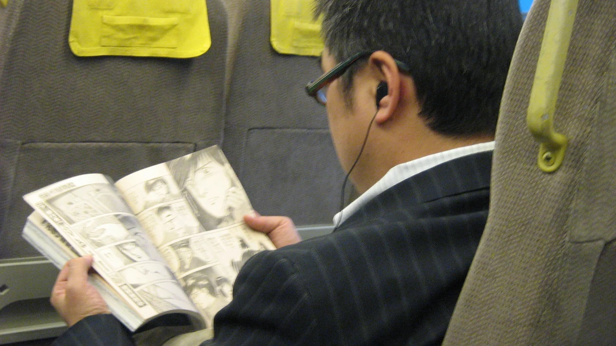 passenger reading illustrated manga tankobon volume during daily city commute