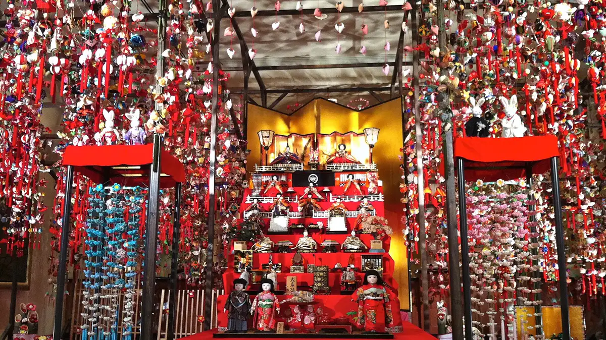 Tiered Hina Doll Display for Girls Day tiered hina doll display with emperor and empress dolls on top, the royal court image behind the himedere princess type