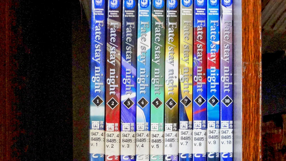 row of manga volume spines adapting the original visual novel on a library shelf
